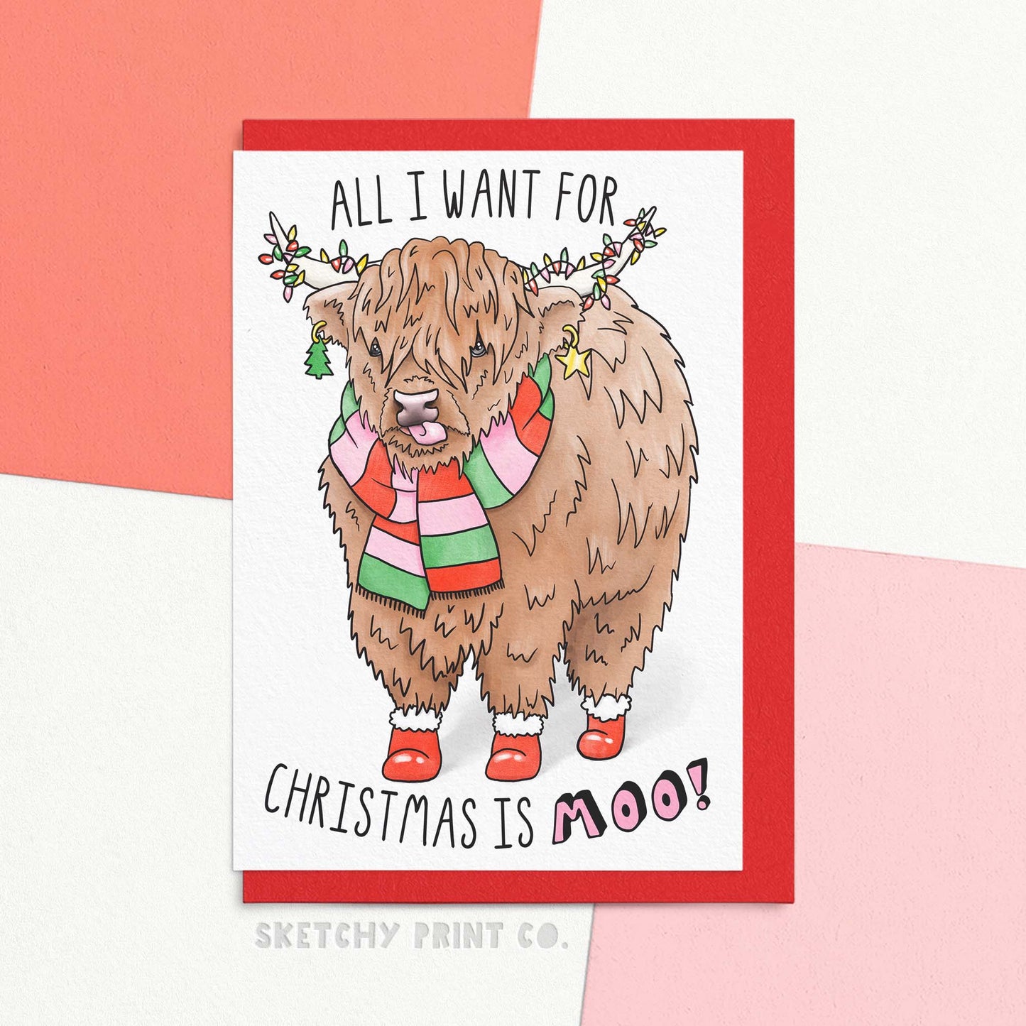 Funny Christmas card with cute Highland cow illustration and text pun 'all I want for Christmas is Moo!'. Shown with red envelope.