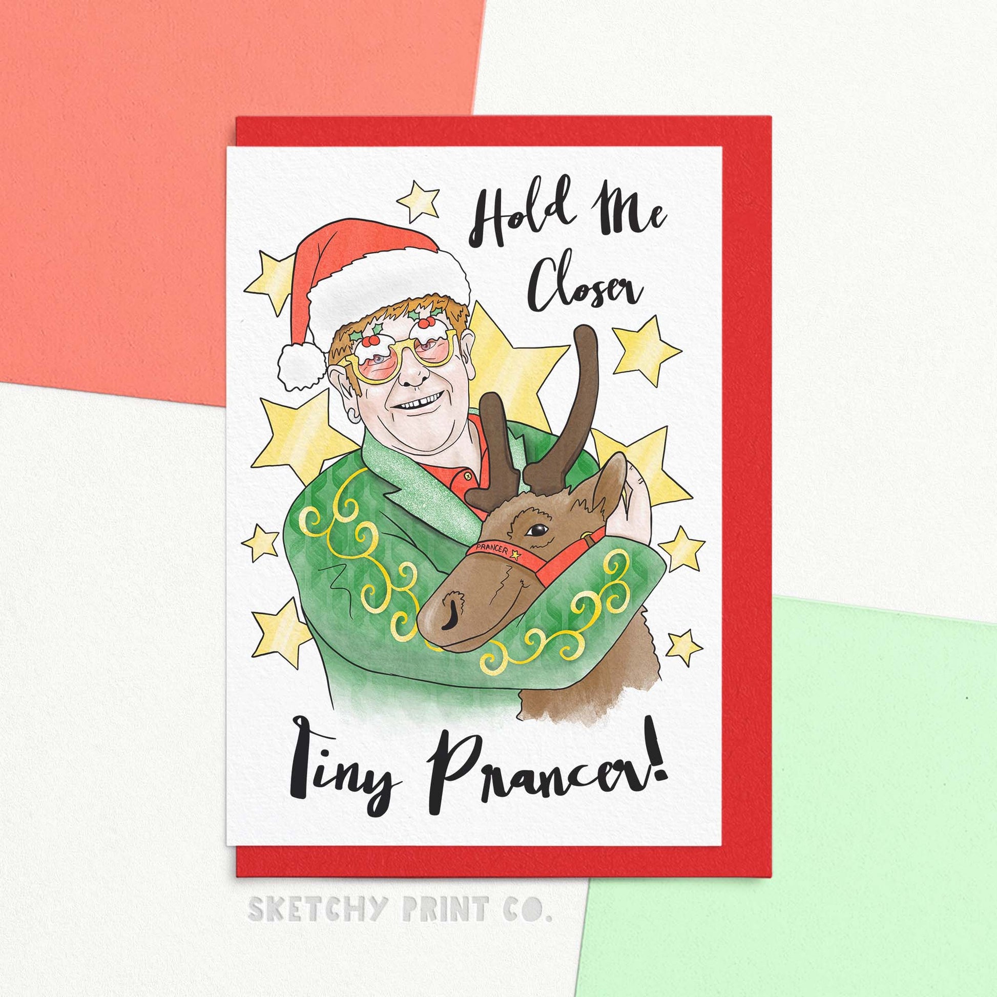 Funny Christmas card reading hold me closer tiny prancer! With an illustration of a man in glasses and Christmas hat hugging a reindeer. Send your friends and family our funny xmas greetings card this Christmas – send funny Christmas wishes with a catchy tune they'll have stuck in their head all day! Printed on FSC paper with compostable packaging – it's the perfect way to send happy Christmas greetings and spread holiday cheer!