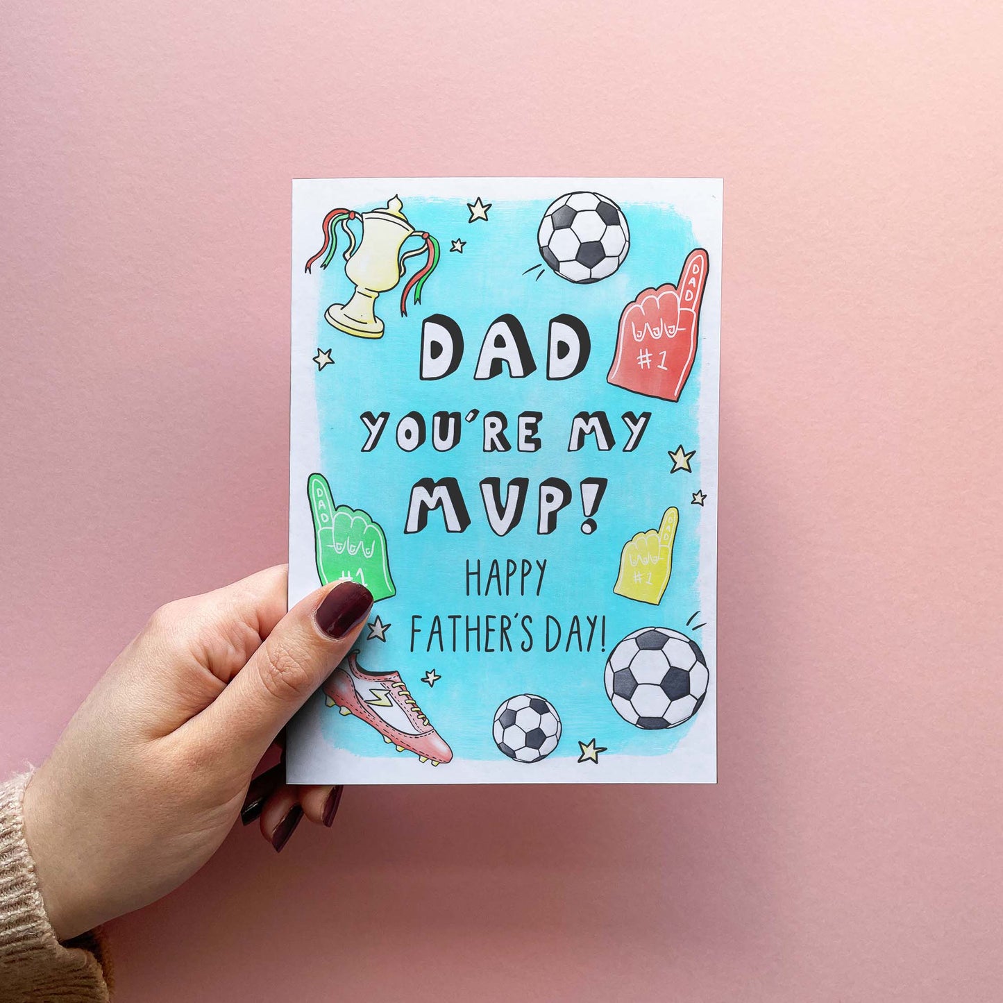 Father's Day card for dad reading 'Dad you're my MVP!' with illustrations of footballs, foam fingers, and trophies. Shown in hand.