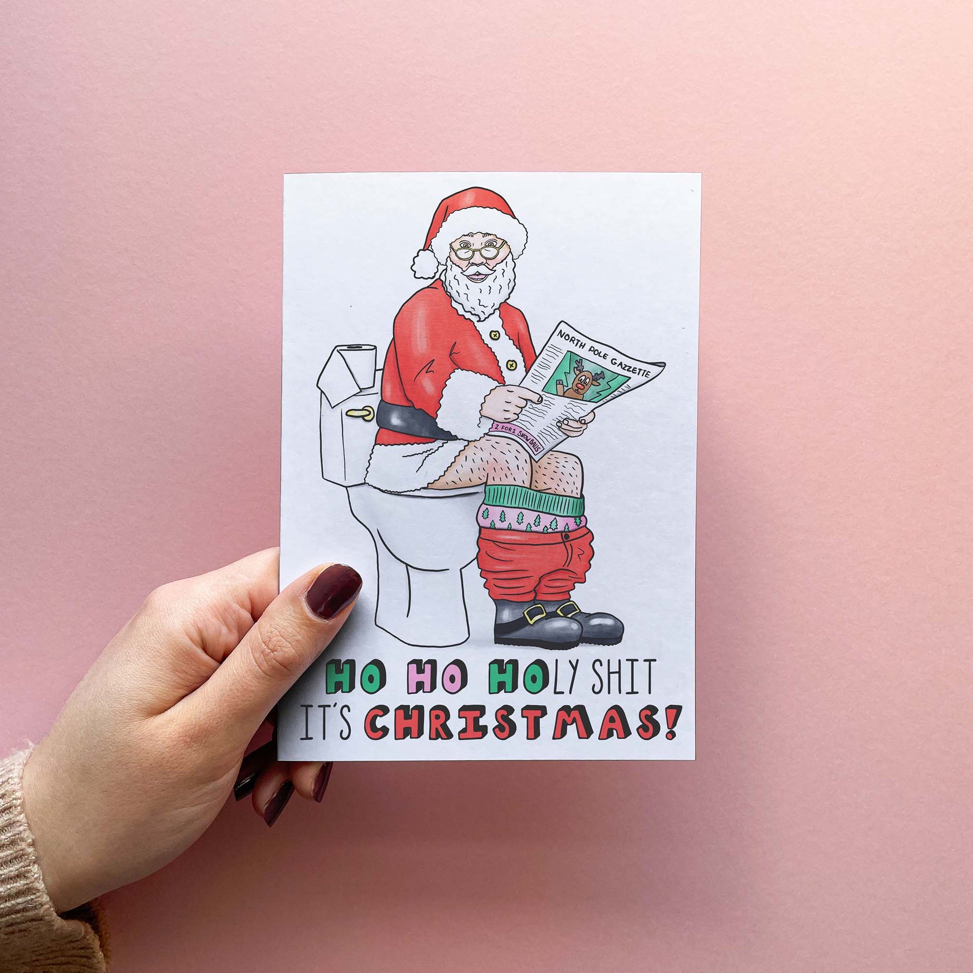 Funny rude Christmas card for husband or boyfriend featuring Santa on the toilet reading a newspaper with the text ho ho holy shit it's Christmas! Get ready to sleigh the holiday season with our cheeky Christmas greetings card! With sacks of toilet humour this card is perfect for when the holiday season sneaks up on you. Spread some unconventional cheer with our rude and hilarious card, yule log not included!