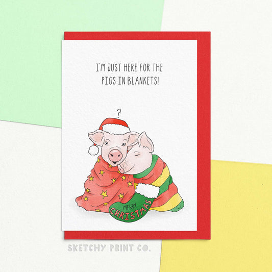 funny Christmas Day wishes card reading I'm just here for the pigs in blankets. With a cute illustration of pigs wrapped up in blankets. Spread some holiday cheer with our merry Christmas card! Featuring a cute design and funny Christmas wishes, this card is perfect for anyone who thinks that pigs in blankets are always the best part of the holiday feast. Send some laughs and love this season!