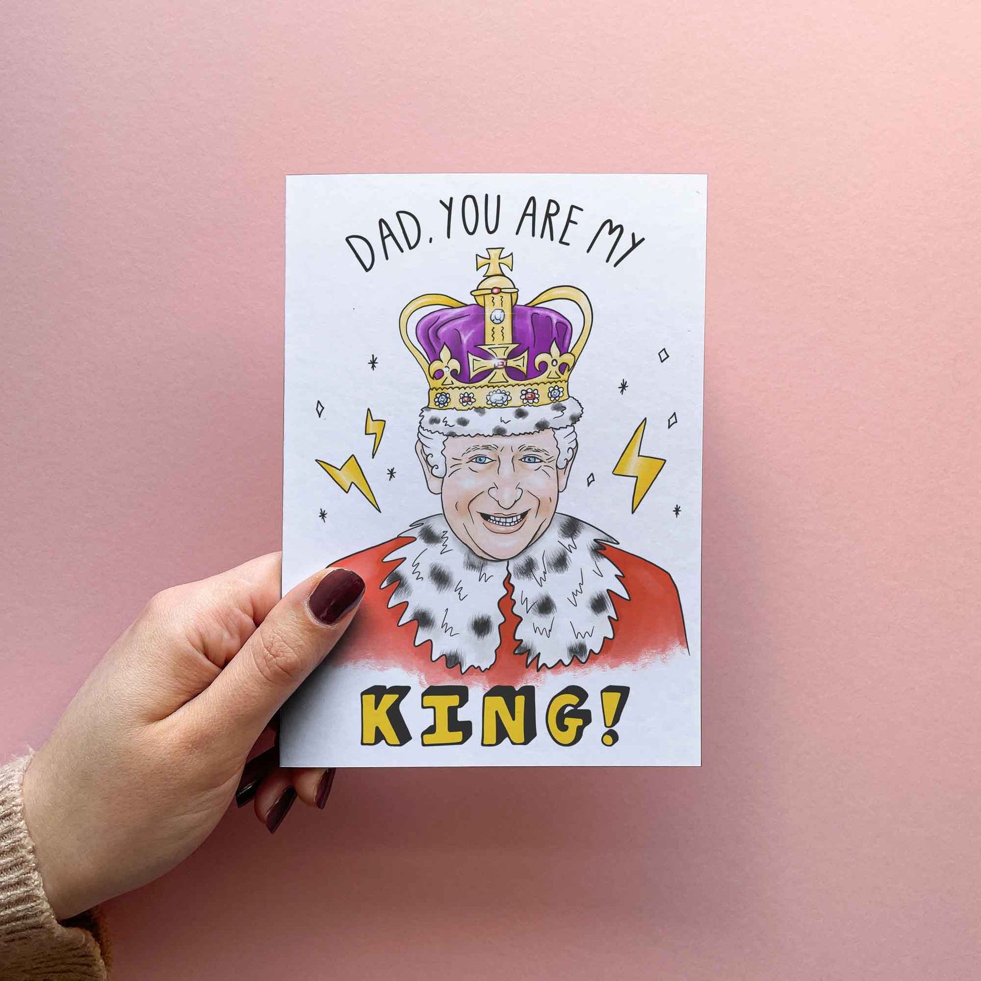 Funny Fathers Day card for Dad, reading: "Dad, you are my king!" illustration of King Charles III wearing crown. If your father jokes about being his royal highness then pair this funny father's day card with a cool gift for dad and make his day! Card shown in hand for size reference.