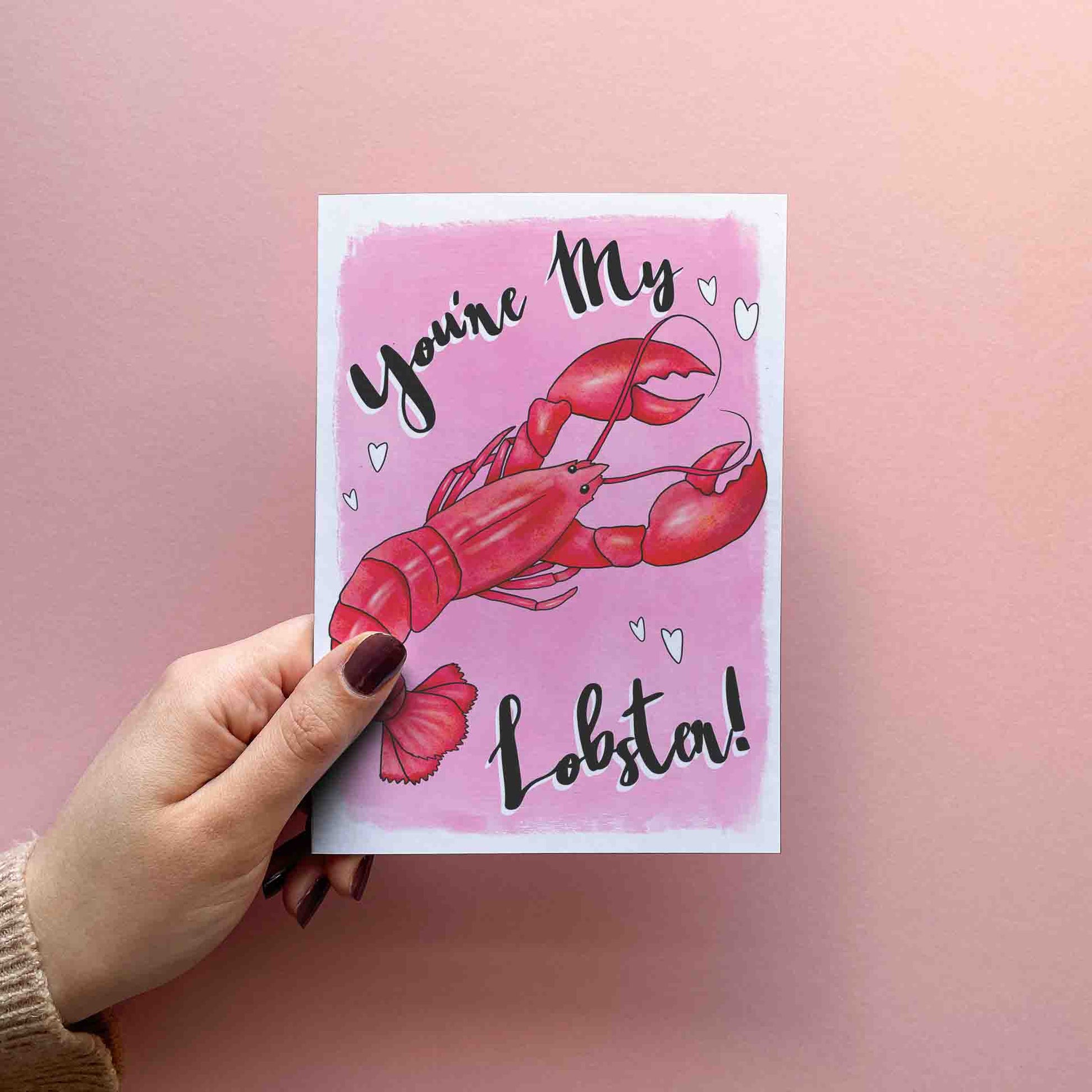 Funny Valentines card for boyfriend or girlfriend reading you're my lobster! A red lobster with a pink background and white hearts. FSC certified paper card with matching red envelope.