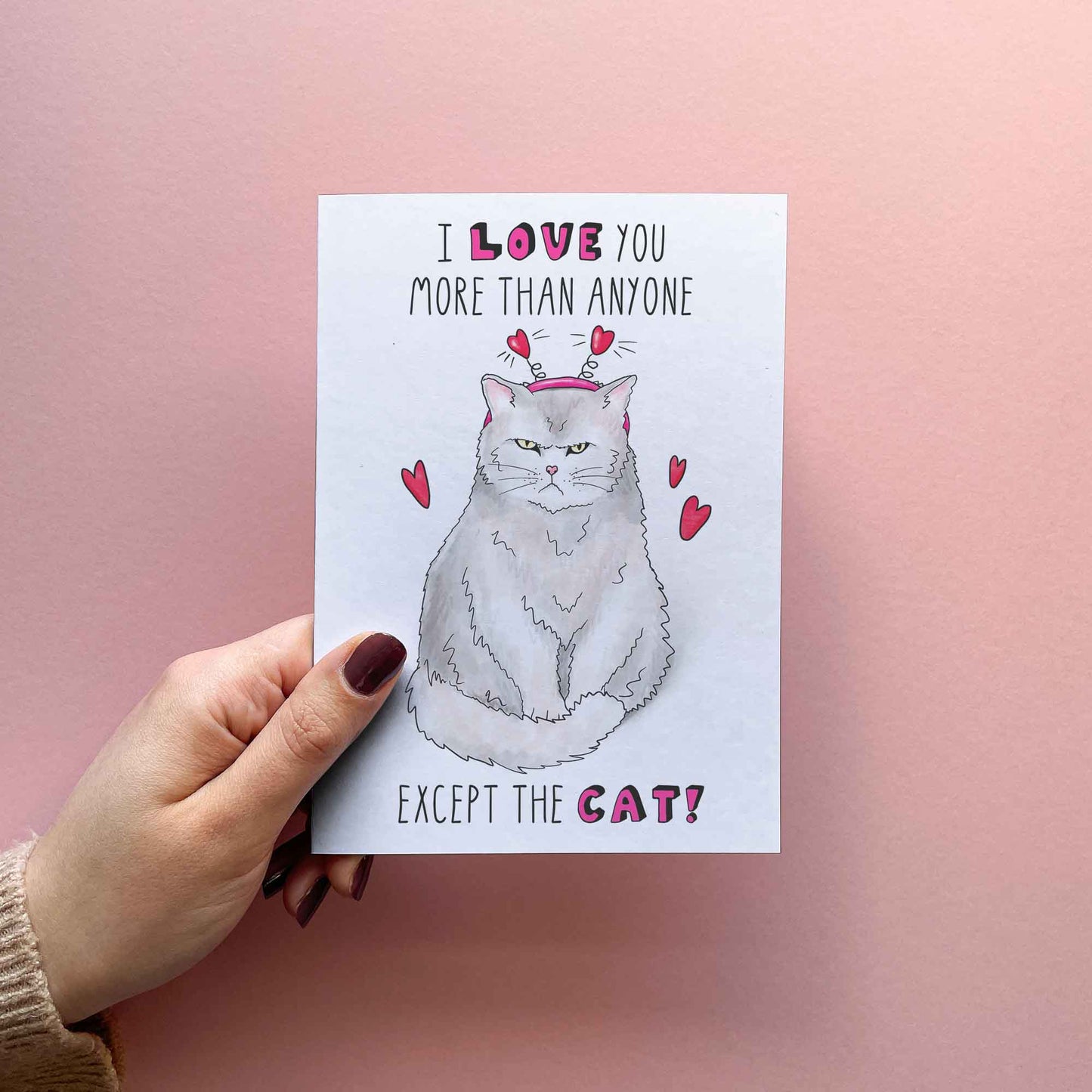 Funny Valentines card for boyfriend or girlfriend, Cat mom or dad. Reading I love you more than anyone except the cat. With illustration of a grumpy cat with red hearts. FSC certified paper card with matching red envelope.